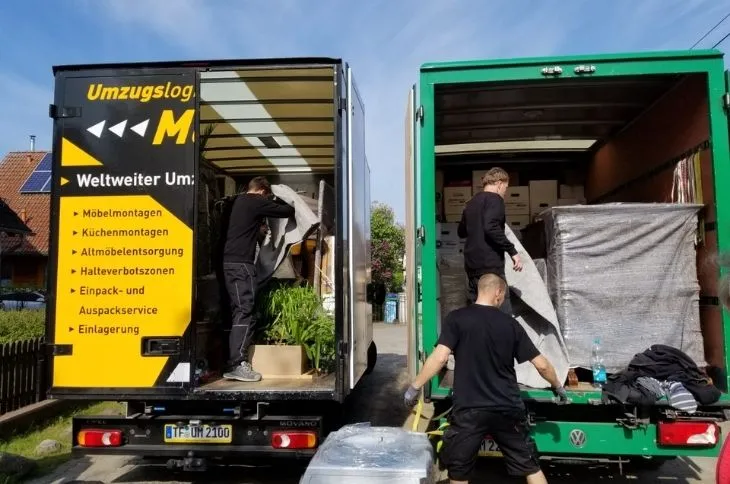 zwei umzugswagen werden parallel beladen